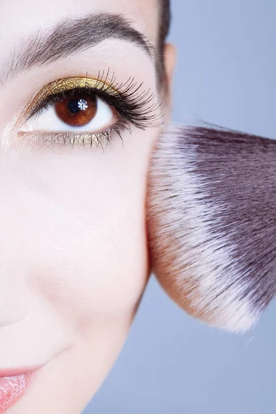 Visage de jeune femme obtenir de la poudre sur sa joue avec un pinceau . — Photo