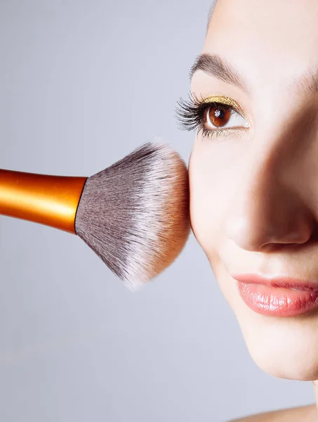 Visage de jeune femme obtenir de la poudre sur sa joue avec un pinceau . — Photo