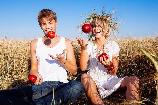 Obrázek mladý muž a žena s jablky na pšeničné pole — Stock fotografie