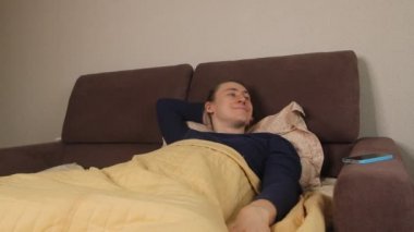  Uykucu Kafkasyalı bir adam sabah uyandığında elinde akıllı bir telefonla sosyal ağları ve haber kaynaklarını kontrol ediyor.