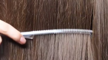 Uzun kahverengi kadın saçlarını taramak için tarak kullanarak, videoyu kapat