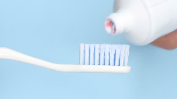 Zahnpasta Auf Eine Bürste Auf Blauem Hintergrund Auftragen — Stockvideo