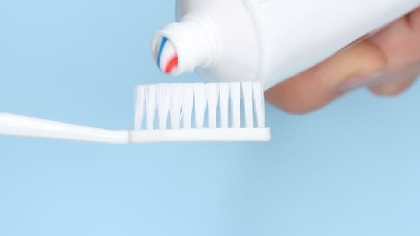 Zahnpasta Auf Eine Bürste Auf Blauem Hintergrund Auftragen — Stockvideo
