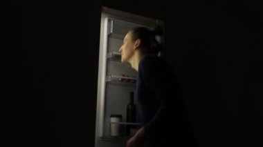Yeme bozukluğu olan aç adam buzdolabına bakıyor ve geceleri yemek yiyor. Sağlıksız yaşam tarzı kavramı