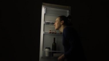 Yeme bozukluğu olan aç adam buzdolabına bakıyor ve geceleri yemek yiyor. Sağlıksız yaşam tarzı kavramı