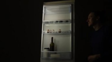 Yeme bozukluğu olan aç adam buzdolabına bakıyor ve geceleri yemek yiyor. Sağlıksız yaşam tarzı kavramı