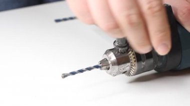 Genç adam elektrikli matkap hazırlıyor ve matkabı değiştiriyor.