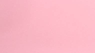 Pembe arka planda tekrar kullanılabilir pembe silikon adet bardağını tutan genç bir kadının ellerini yakın plan. Sıfır atık adet hijyen konsepti.