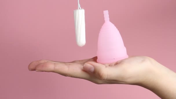 一个年轻女子手拿着粉红背景的可重复使用的粉红硅胶月经杯 零废物月经卫生概念 — 图库视频影像