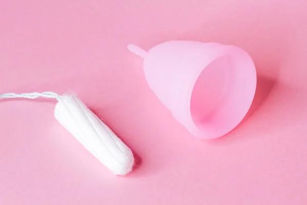 Mulheres mãos segurando copo menstrual de silicone rosa reutilizável no fundo rosa — Fotografia de Stock