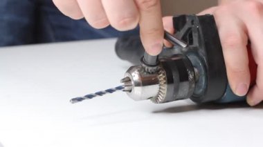 Genç adam elektrikli matkap hazırlıyor ve matkabı değiştiriyor.