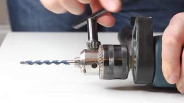 Genç adam elektrikli matkap hazırlıyor ve matkabı değiştiriyor.