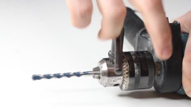 Genç adam elektrikli matkap hazırlıyor ve matkabı değiştiriyor.
