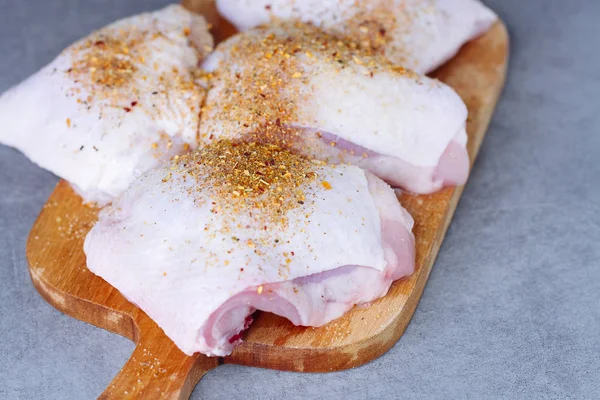 Raw kycklinglår med örter på skärbräda på grått bord — Stockfoto