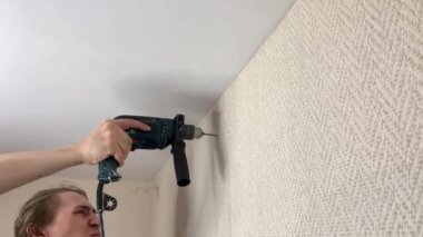 Adam korniş asmak için duvarı deliyor. Duygusal ifade yüz ifadesi