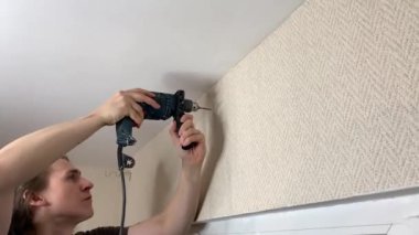 Adam korniş asmak için duvarı deliyor. Duygusal ifade yüz ifadesi