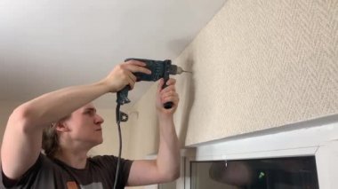 Adam korniş asmak için duvarı deliyor. Duygusal ifade yüz ifadesi