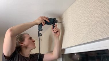 Adam korniş asmak için duvarı deliyor. Duygusal ifade yüz ifadesi