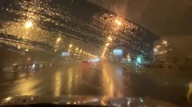 Gece kenti ıslak pencereden silecekli hareket eden bir arabanın içinde. Yağmurlu karanlık gece manzaralı şehir yolu 