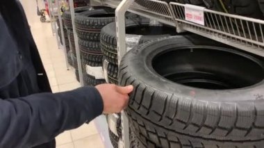 Otomobil lastikleri hipermarket otomotiv bölümü üzerinde seyir ve üzerlerine basarken seçmek çalışırken genç adam