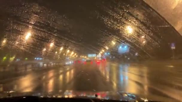 夜市通过湿淋淋的车窗用雨刷移动 市区道路多雨的夜景 — 图库视频影像