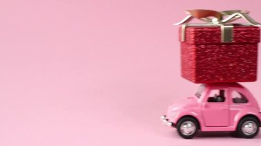 Moskova, Rusya - 5 Aralık 2019: pembe arka planda kırmızı hediye kutusu teslim eden pembe retro oyuncak araba. Yeni yıl, Noel, Sevgililer Günü konsepti
