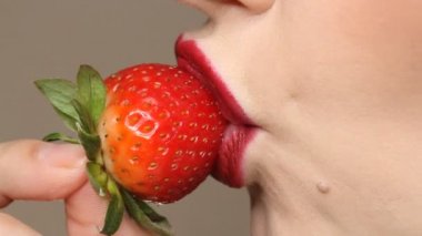 Kadın mastürbasyon taklidi yapıyor. Şehvetli kırmızı dudaklar çilek yalıyor. Seksi kadın dili ve dudakları