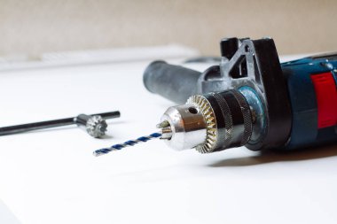 Genç adam elektrikli matkap hazırlıyor ve matkabı değiştiriyor.