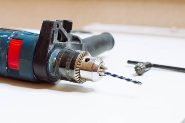 Genç adam elektrikli matkap hazırlıyor ve matkabı değiştiriyor.