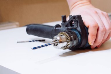 Genç adam elektrikli matkap hazırlıyor ve matkabı değiştiriyor.