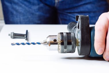 Genç adam elektrikli matkap hazırlıyor ve matkabı değiştiriyor.