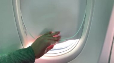 Kadın eli uçağın penceresini açıyor. Bulutlar ve gökyüzü bir uçağın, bir uçağın penceresinden görülebiliyor..
