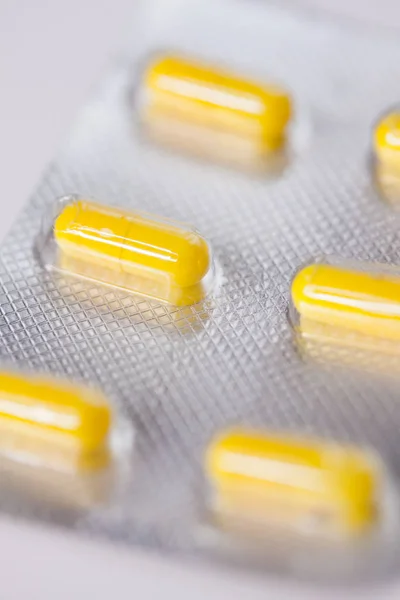 Close up of yellow  tablets, pills in blister pack, medications drugs, macro, selective focus — Stockfoto