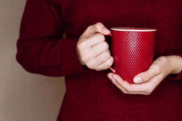 Mujer joven en suéter rojo está sosteniendo la taza roja de té o café . — Foto de Stock
