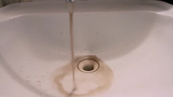 Zblízka špinavé rezavé hnědé znečištěné vody tekoucí z kohoutku v koupelně dřezu. — Stock video