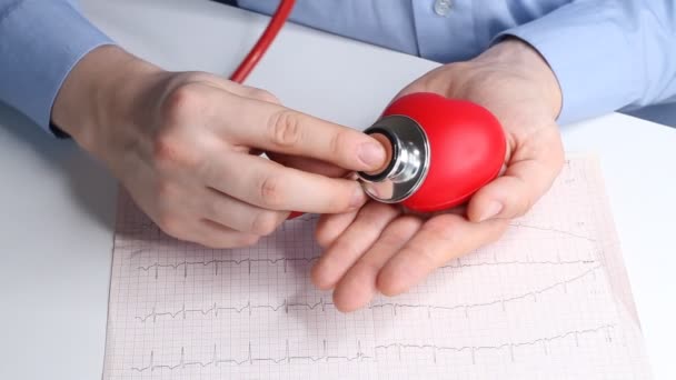 心臓科医はおもちゃの赤い心臓の心拍数をチェックします 電話内視鏡 聴診器や心臓 ヘルスケアと早期診断の概念 — ストック動画