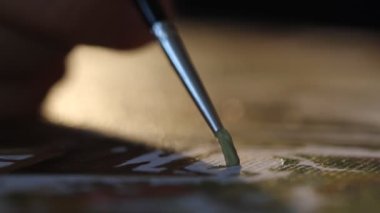 Sanatçı fırçasına yakın çekim. Resim stüdyosunun arka ışıklarındaki tuvale resim yapmak. Modern sanat eseri yaratmak. Hobi ve eğlence konsepti