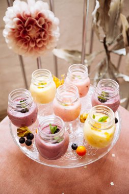 Güzel dekore edilmiş yemek masası pembe masa örtüsü üzerine smoothie.