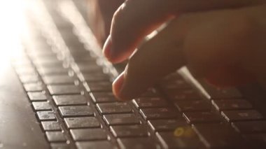 Close up shot of man typing on laptop keyboard; backlit; news, writer, media or communication concept