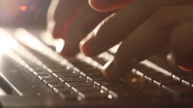 Close up shot of man typing on laptop keyboard; backlit; news, writer, media or communication concept