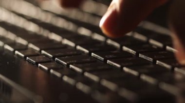 Close up shot of man typing on laptop keyboard; backlit; news, writer, media or communication concept