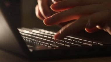 Close up shot of man typing on laptop keyboard; backlit; news, writer, media or communication concept
