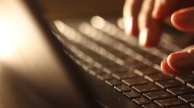 Close up shot of man typing on laptop keyboard; backlit; news, writer, media or communication concept