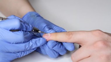 Erkek tırnaklarıyla ilgilenmek. Salondaki mavi eldivenli manikürcü bir erkek için manikür yapıyor. Erkeklerin güzellik konsepti