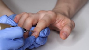 Erkek tırnaklarıyla ilgilenmek. Salondaki mavi eldivenli manikürcü bir erkek için manikür yapıyor. Erkeklerin güzellik konsepti