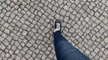 Siyah spor ayakkabılı ayaklar sett yol üzerinde adım şehir üzerinde yürüyor