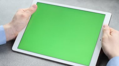 Adam yeşil ekranla tabletin ekranına dokunup bakıyor. Krom anahtar iş adamının elindeki tabletin ekranında.