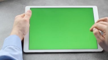 Adam yeşil ekranla tabletin ekranına dokunup bakıyor. Krom anahtar iş adamının elindeki tabletin ekranında.