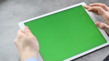 Adam yeşil ekranla tabletin ekranına dokunup bakıyor. Krom anahtar iş adamının elindeki tabletin ekranında.