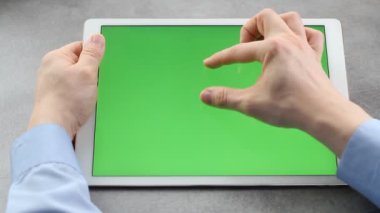 Adam yeşil ekranla tabletin ekranına dokunup bakıyor. Krom anahtar iş adamının elindeki tabletin ekranında.